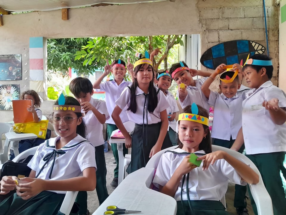Students in school uniforms wearing paper crowns they made in class.
