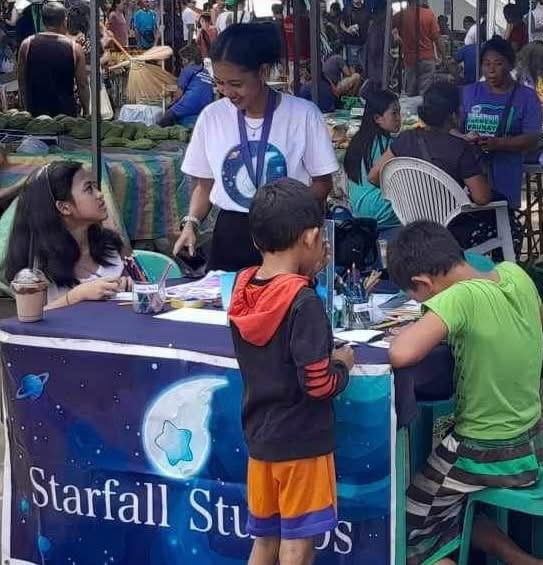 Children gather at the studio table at an outdoor event.