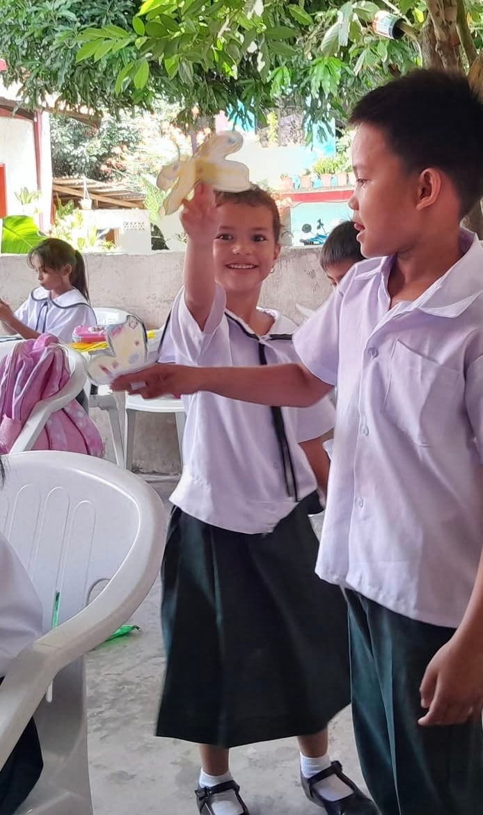 A student holds up a flower drawing in a classroom.