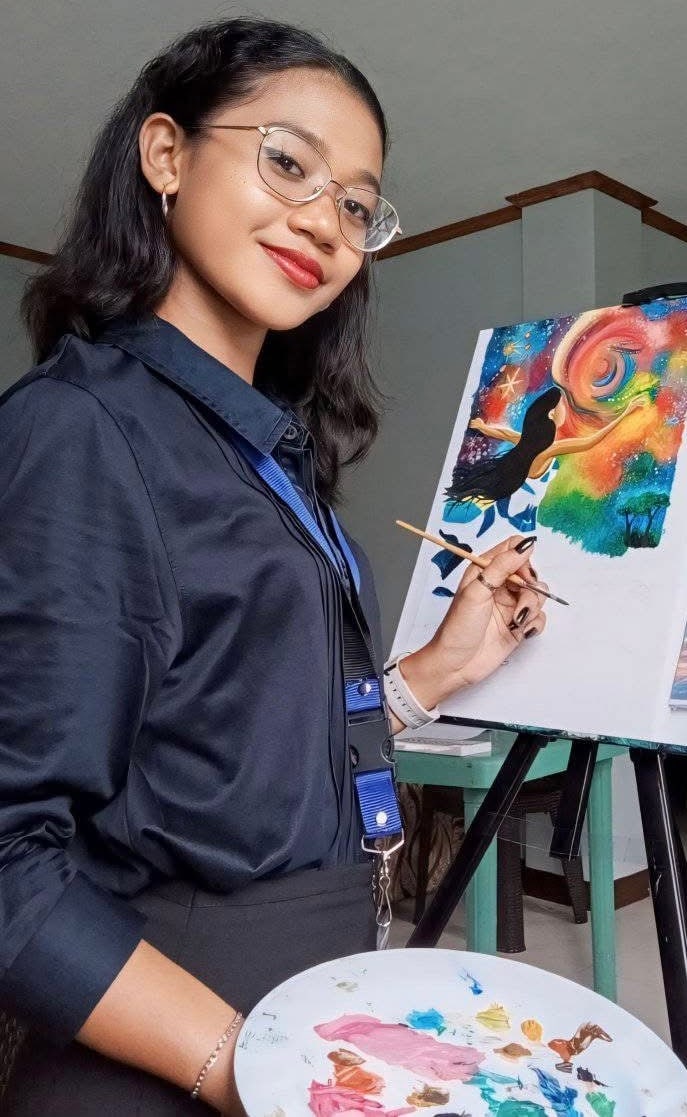 A young artist smiles while painting a colorful canvas.