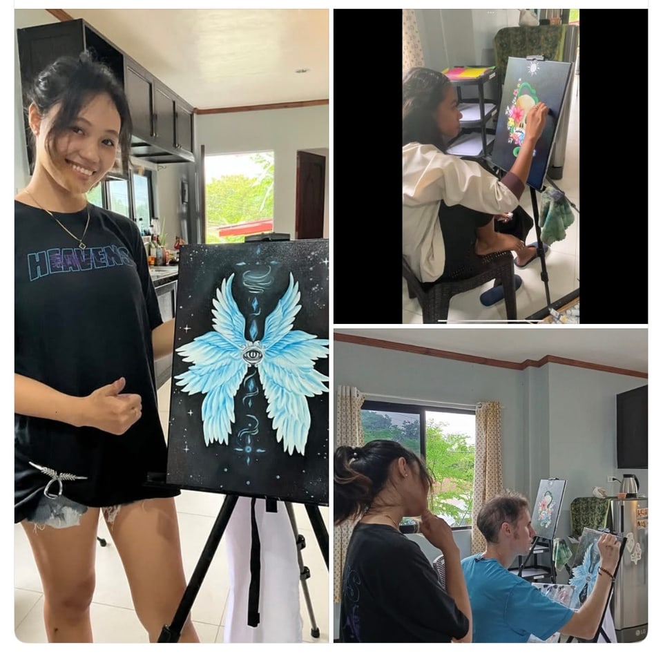Two friends show a finished painting of blue wings, and an art class in progress.